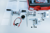 The picture shows an experiment kit that includes various components such as a motor, clamps, cables and instructions for learning experiments. It is used for practical experiments in the field of physics education.