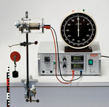 The picture shows an experimental device with an electric motor, a display clock and a control and power supply unit. The setup is designed for practical experiments in the field of physics or technology in education.