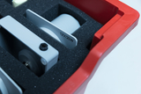 The picture shows a red container lined with foam and containing various technical components. One of the visible labels indicates a voltage of 12V and a power of 20W.