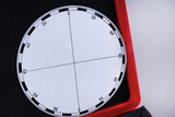 The image shows a white measuring disc with a scale from 0 to 90 degrees in four quadrants, presented in a red frame. This disc is probably used for educational experiments to perform angle measurements.