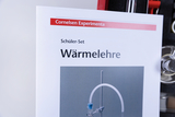 The picture shows instructions for a student set on thermodynamics from the Cornelsen range. In the background you can see various laboratory equipment that can be used for experiments in thermodynamic research.