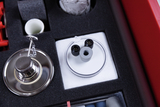 The picture shows a selection of experimental materials sorted in a padded case. Among other things, you can see a metal ring with a chain and a transparent disc with two black threaded elements.