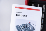 The picture shows a brochure entitled &quot;Electronics&quot; from a student set from Cornelsen Experimenta. In the background, components of an experiment set for electronics are shown, which can be used for practical testing.