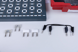 The picture shows an experimental board with several round holes and a number of components, including resistors and cables with terminals. These components are typical for use in experiments in the field of electrical engineering.