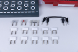 The picture shows an arrangement of various electrical components, including connectors with different resistances and a connecting cable. In the background you can see a gray connection board with round holes for mounting the components.