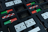 The picture shows a set of experimental materials arranged in a foam-padded container. It contains various components such as spring contacts, wires and components with labels that indicate different values.