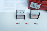 The picture shows several coils with different winding numbers (300, 600, 1200 turns) as well as two stones with red markings that probably serve as magnets. Instructions on induction and alternating current are also visible and are part of the experiment set.