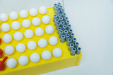 The picture shows a yellow experimental device equipped with white and gray building blocks. The white balls are evenly arranged, while the gray tubes are arranged in several rows, indicating a teaching tool for scientific experiments.