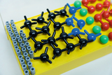 The picture shows a model for representing molecules, which consists of various colorful plastic balls and connecting rods. The elements are arranged on a yellow base to clearly represent chemical structures.