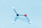 The image shows a molecular model made up of colorful spheres and connecting rods. The spheres represent different atoms, typically oxygen, carbon and hydrogen, and are arranged on a light blue background.
