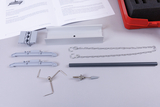 The picture shows various experimental materials, including brackets, chains and a grey pipe, possibly intended for physics or engineering experiments. Next to the materials lies a manual with instructions on a white background.