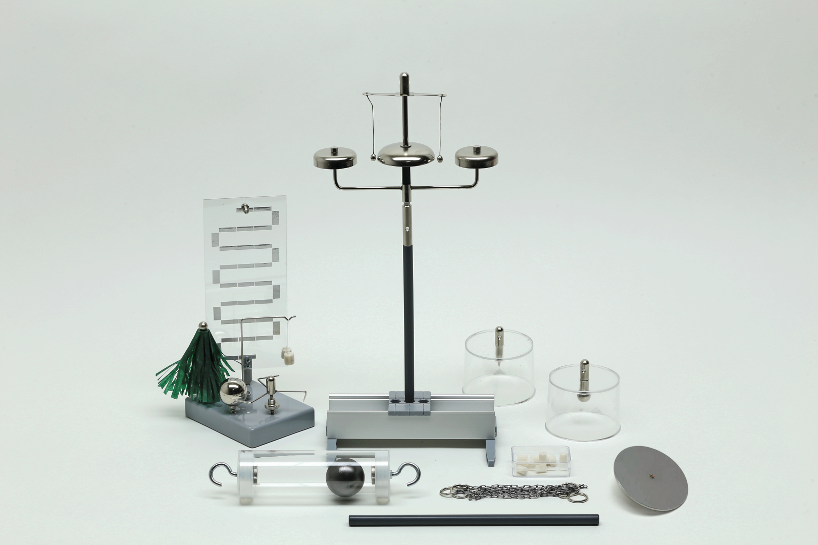 The picture shows a collection of experimental materials, including a weighing bridge, transparent cylinders and various weights. These utensils are designed for experimental use in education and enable practical physical investigations.