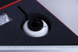 The picture shows an experimental device stored in a precisely fitting foam insert. Next to the device there is a transparent packaging with additional parts or accessories, as well as a metric ruler for precise measurements.