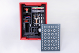 The picture shows a red box containing various experimental materials for educational purposes, including electrical components and a mounting board with numerous connection options. The box is clearly structured to facilitate practical application in experiments.