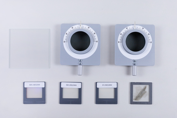The picture shows two optical devices with round openings and scales, as well as several special foils with different lines/mm (600, 300 and 80). Also visible is a square piece of glass, presumably used in experiments.