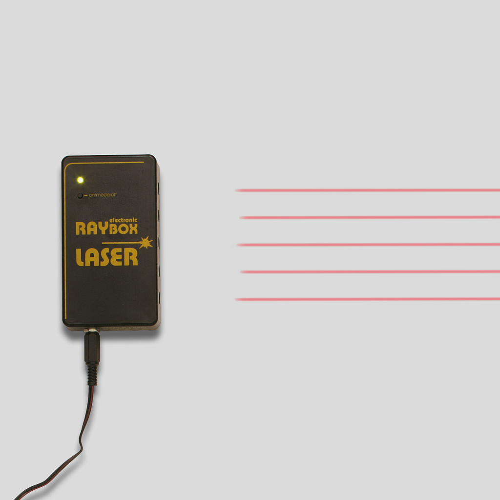 The picture shows a compact device called &quot;electronic RAYBOX LASER&quot; that generates a laser beam. The beam is shown as several red lines extending from the device to the right.