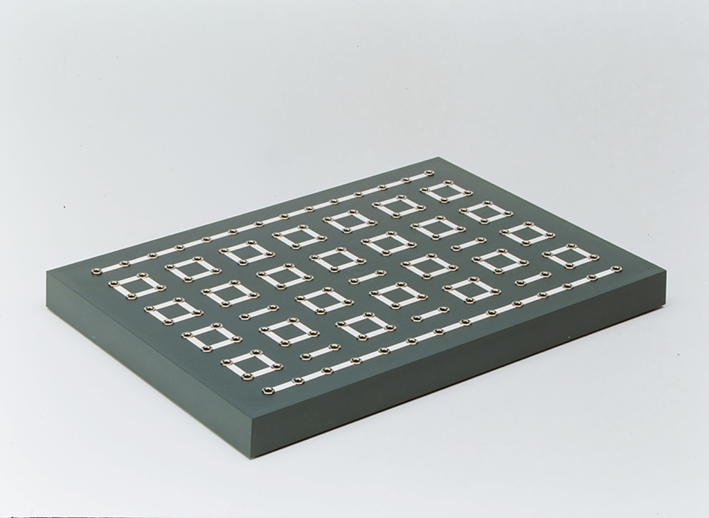 The image shows a gray platform with several rectangular contacts evenly spaced. This structure appears to be designed for experimental purposes in education, possibly for conducting electrical experiments or circuits.