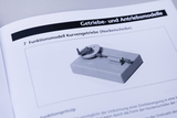The picture shows a functional model of a cam mechanism (cam disk) on a described surface. It illustrates how a rotary motion is converted into another motion by the shape of the cam disk.