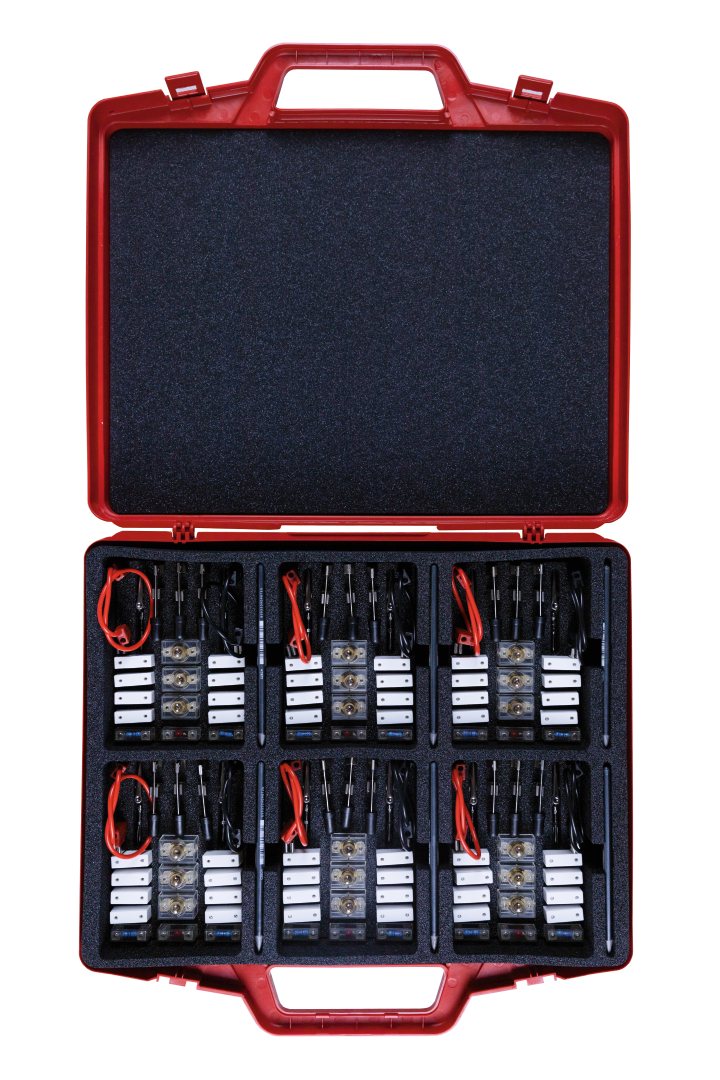 The picture shows a red case with a textured foam insert in which several experimental devices and cables are organized. The arrangement includes various electronic components designed for teaching purposes in education.