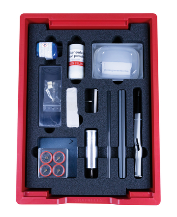 The picture shows an experiment kit arranged in a red box, with various materials such as iron powder, a magnet and several tubes. This set is designed for school experiments in the field of physics and magnetism.