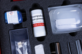 The picture shows a collection of experimental materials in a foam-filled case. Among other things, you can see a bottle of iron powder and a container of copper sulfate, which can be used for chemical experiments in the educational field.