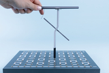 The picture shows a chemical experiment device held by a person. It consists of a stable base with attached metal joints and a vertical rod to which a movable element is attached, which can be used for experiments.