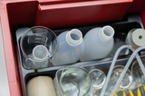 The picture shows a collection of laboratory equipment in a red box, including beakers, plastic bottles and various transparent tubes. The equipment is ideal for experimental work in education.