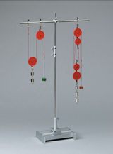 The picture shows an experimental device with a stand and several red rollers on which weights are placed in different positions. This apparatus is used to carry out physical experiments, for example to demonstrate forces and movements.