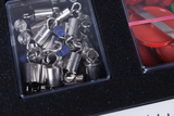 The picture shows a collection of silver metal weights with hooks and blue plastic parts in a transparent box. Next to them, red round objects are visible, which are also kept in a transparent container.