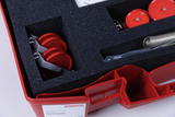 The picture shows a red storage kit containing mechanical parts, including two red-painted rollers and several metal components, safely stored in a foam-padded interior. It is an experimental kit for the German educational system.