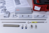 The picture shows a mechanics experiment set, consisting of various metal components such as rods, springs and hooks, as well as a force gauge. Instructions and a red storage box can also be seen, which complete the set.