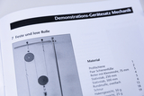 The picture shows a page from a manual for demonstration equipment for mechanics in education. It contains details of an experiment with fixed and loose pulleys and a list of materials.