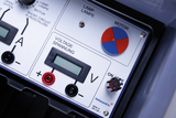 The picture shows a control panel of an experimental device with various switches and displays. Components for measuring voltage and current as well as controls for a lamp and a motor can be seen.