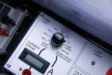 The picture shows an electrical experimental device with a control and display panel. You can see adjustment knobs for resistance and current as well as connections for different loads such as lamps or motors.