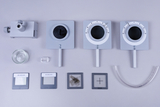 The picture shows a selection of experimental equipment, including measuring instruments such as a deflection tube and various microscope slides. In addition, a glass container and a transparent tube can be seen, which can be used for physics experiments.
