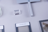 The image shows various experimental materials, including a clear crystal, a tool with a long handle, and several plates with labels on them. These objects appear to be intended for scientific or educational experiments.