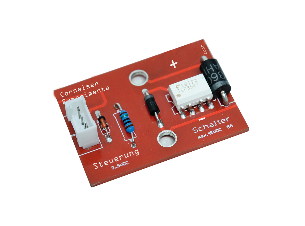 The picture shows a red circuit board with several electronic components, including resistors, transistors and a switch. The plaque is designed for educational use and has labels for control and maximum voltage values.