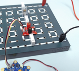 The picture shows an experiment board with electrical components, including a module with connectors and a battery. Flexible connecting wires enable various electrical connections for experimental purposes in education.