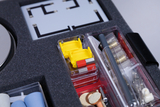 The picture shows an open box with experimental supplies, which contains various components for scientific experiments. You can see yellow components, tools and materials that are designed for use in the educational sector.