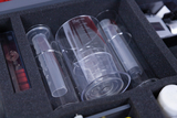 The picture shows a selection of transparent laboratory glassware and measuring instruments neatly stored in a foam tray. These materials are typical accessories for experiments in educational settings, especially in chemistry and physics.