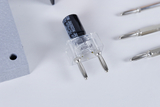 The picture shows a capacitor with a capacity of 4700 μF and several precision tools. The capacitor has a transparent case showing its terminals and the tools are suitable for experimentation and construction projects.