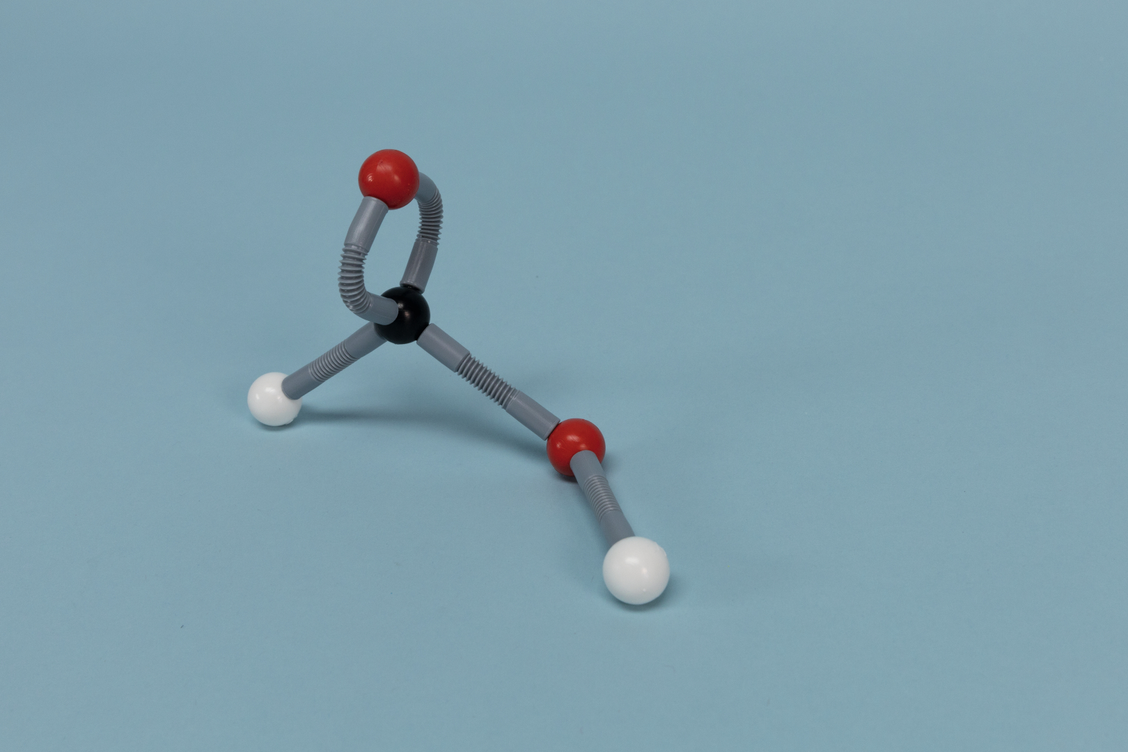 The image shows a molecular model with different colored spheres representing atom types: red for oxygen, black for carbon and white for hydrogen. It is placed on a blue background and is used to illustrate chemical structures.