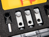 The image shows a textured foam insert from an experiment kit with several silver apparatuses and a black plastic part. The parts appear to be designed for conducting physics or chemistry experiments in an educational setting.