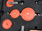 The picture shows a set of red rollers and elements arranged in a foam pad. These parts probably belong to an experimental system used for educational purposes in the STEM field.
