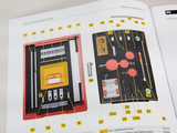 The picture shows a clear representation of a student mechanical experiment kit containing various components in a red box. Each part is numbered and annotated to facilitate its use in education.