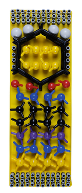 The picture shows a model building set for the representation of molecules, consisting of different colored balls and rods that symbolize atomic structures. The set is on a yellow base and is intended to promote scientific learning in the educational field.