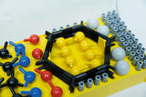 The picture shows a model kit with various colorful balls and rods, which is used to represent molecular structures. It is arranged on a yellow base and is suitable for use in education, especially in chemistry lessons.