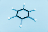 The image shows a model of a molecule composed of colorful rods and spheres to represent chemical bonds and structures. It consists of a hexagonal shape with several atoms attached to it and is placed on a blue background.