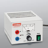 The picture shows an electrical experimental device with a white housing that has connections for positive and negative poles and a rotary control for voltage adjustment. A scale shows the voltage in volts and the device has a power switch.