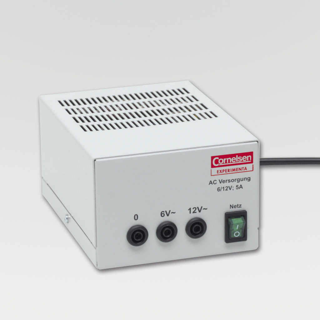 The picture shows a white power supply unit with a ventilation grille and three connections for voltages of 0, 6V and 12V. It is a product of the Cornelsen brand, which is designed for experimental use in education.